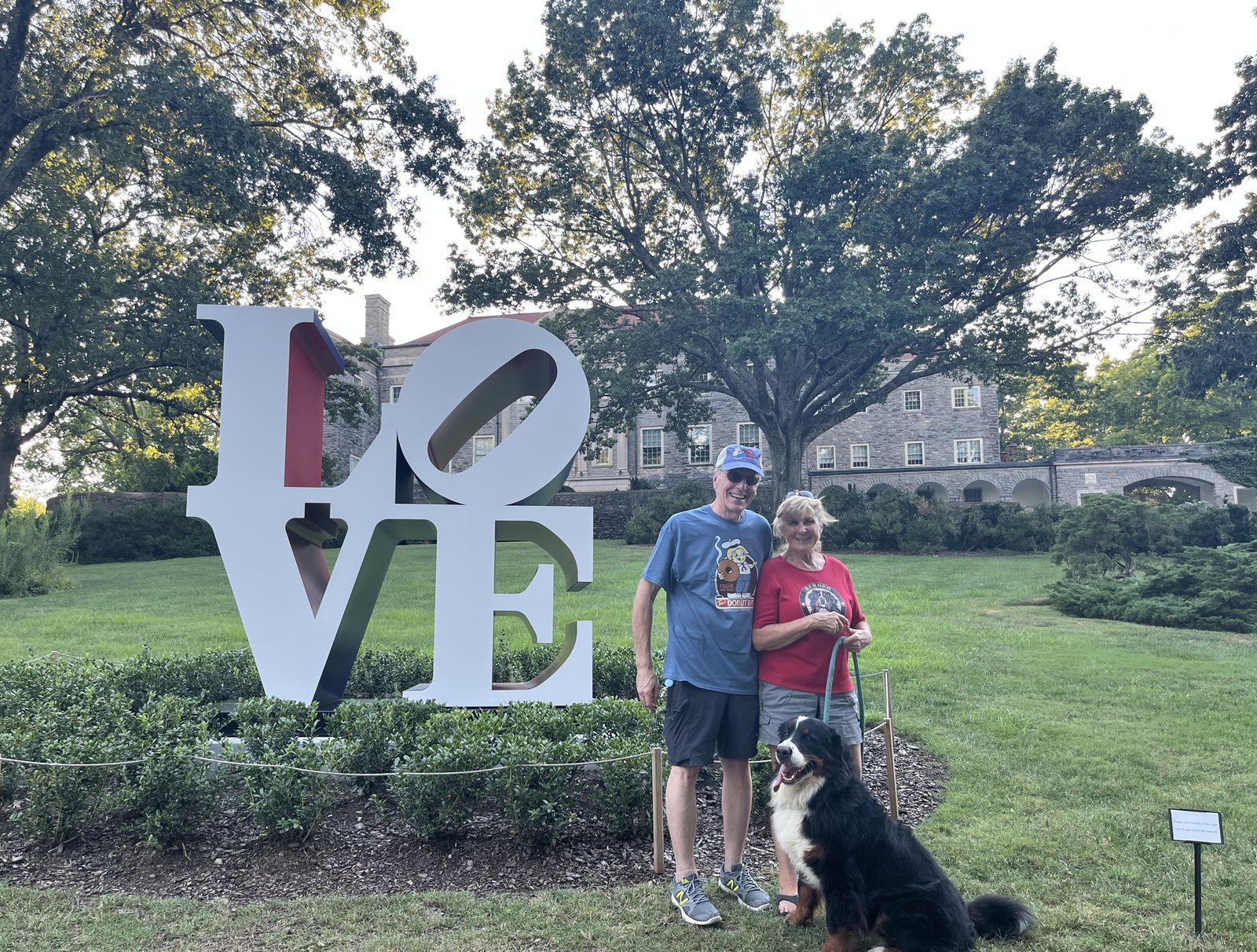 Cindy with her husband and Bernese Mountain Dog at a LOVE sculpture in a Nashville garden.